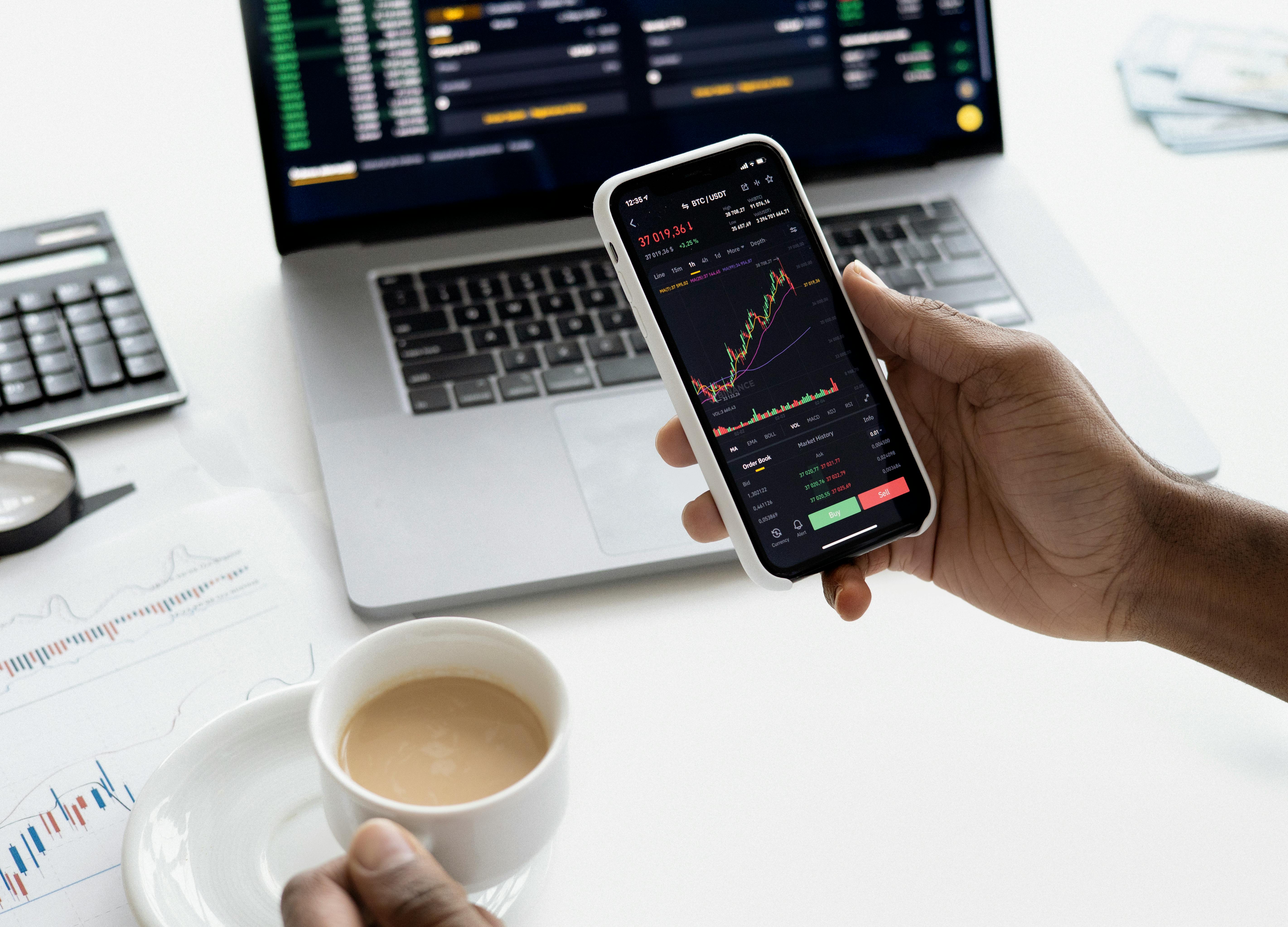 Professional trader monitoring forex charts on mobile and laptop